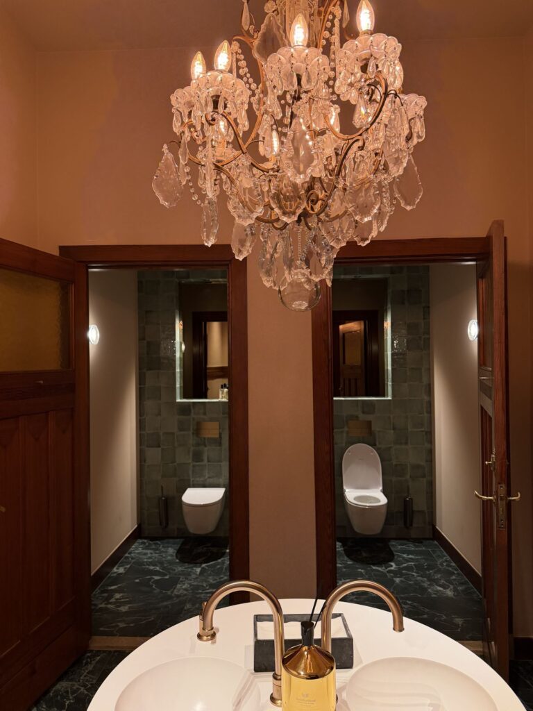 Luxe badkamerinterieur met kroonluchter, donkere lambrisering en wastafel