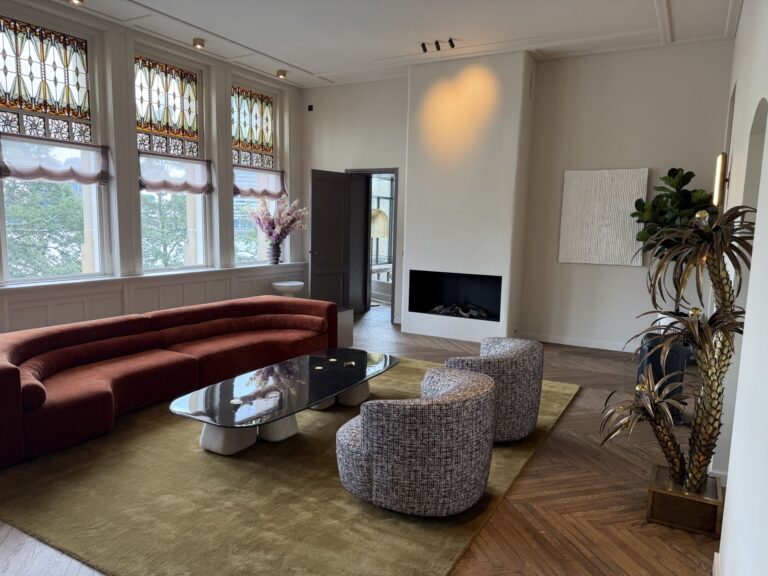 Woonkamer met gebogen bank, haard en monumentale ramen